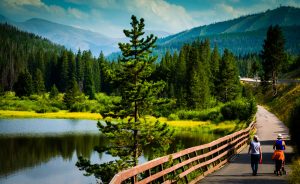 A couple walking on a mountain trail beside a lake.